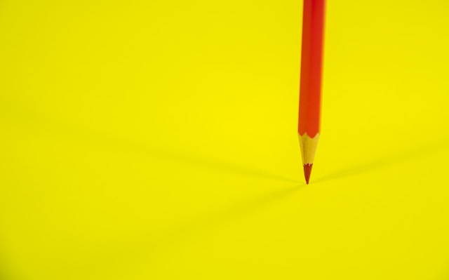 Symbolbild: Roter Stift auf gelbem Grund